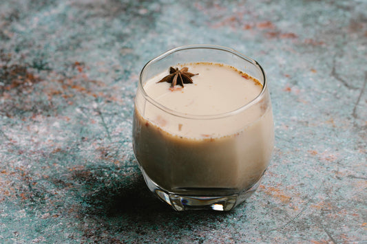 Chai latte on stone top in a clear glass with a star anis floating on top