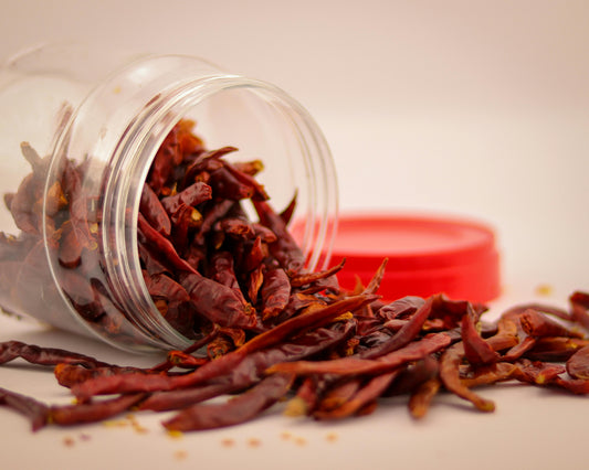 Cayenne pepper chillis in a clear plastic jar with a red lid