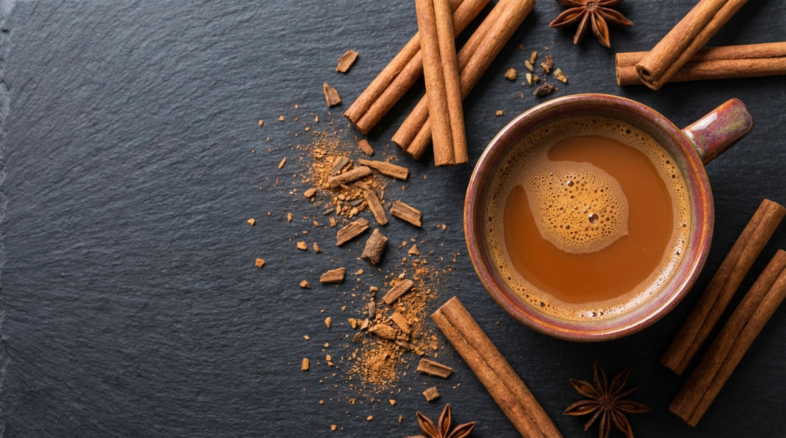 Cinnamon sticks and ground cinnamon with a warm chai tea on dark slate