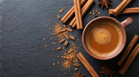 Cinnamon sticks and ground cinnamon with a warm chai tea on dark slate