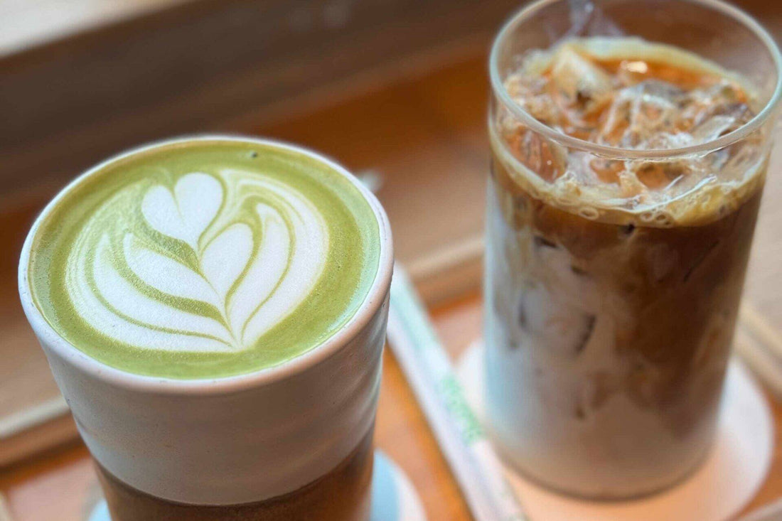 Matcha latte beside an iced coffee in a glass cup with a straw on coasters