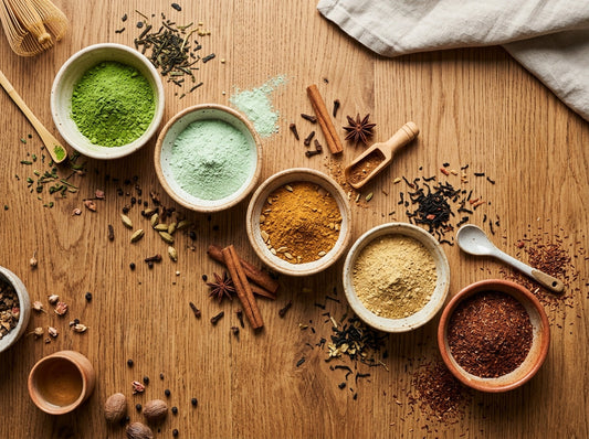 Five small bowls of different microground tea powders arranged on a wooden surface in warm natural light