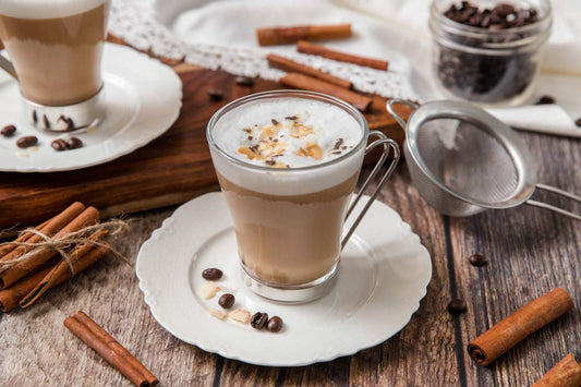 A dirty chai latte shown with espresso beans and cinnamon on a saucer
