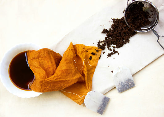 Tea bags and microground tea beside a cup of chai tea