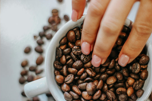 Hand reaching for coffee beans in a mug