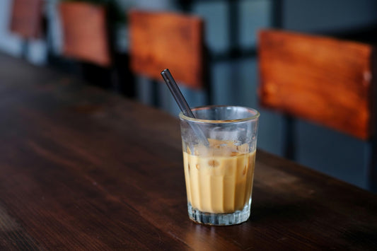 An iced london fog latte on a wooden table in a glass cup with a straw