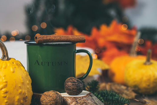 Tea in a green autumn mug with fall decorations like pumpkins and leaves