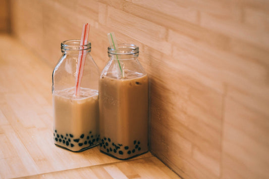 Milk bubble tea with tapioca, brown in colour likely brown sugar. In glass square milk bottles